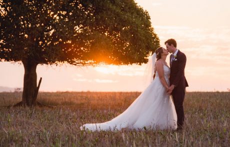 bride and groom kissing with sunset